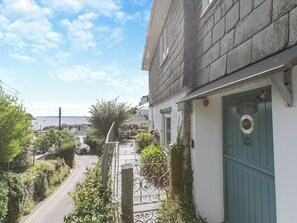 A narrow street with a building on the right, a green door, and a view of the sea in the background. - 4 bedroom accommodation in St. Mawes (St. Mawes)