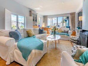 A spacious living room with two white sofas, a coffee table, and a view of the outdoors.