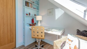 A study with a desk, chair, bookshelf, and a small ship model. - 4 bedroom accommodation in St. Mawes (St. Mawes)
