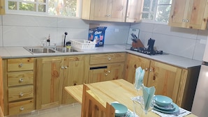 Una cocina con armarios de madera, un fregadero, una estufa y una mesa de comedor con vajilla azul.