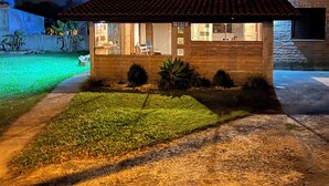 A two-story house with a tiled roof, a visible number '1830' on the side, and a well-maintained lawn. - Garden house with two bedrooms (Tramandaí Tramandaí)