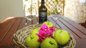 A wicker basket with green apples and pink flowers on a wooden table. - Green Garden Apartment (Hvar)