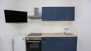 A compact kitchen with a built-in oven, a sink, and blue cabinets. - Green Garden Apartment (Hvar)