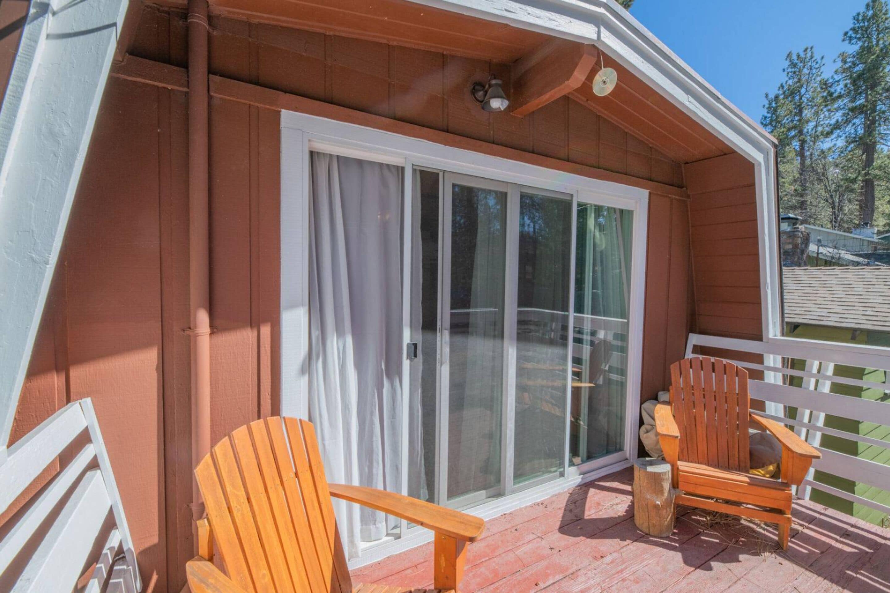 A wooden deck with two wooden chairs and a white railing.