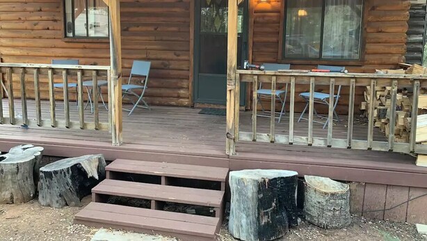 Una cabana de fusta amb un porxo, dues finestres i una porta.