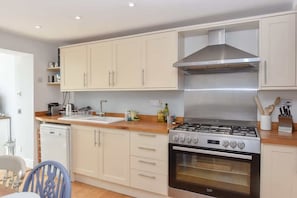 A kitchen with a gas stove, oven, and white cabinets.