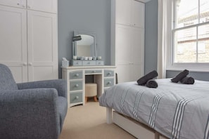 A bedroom with a bed, a dresser, a chair, and a window.