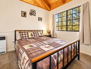 Un dormitorio con una cama grande, una ventana con cortinas, un calentador fijado a la pared y un cartel que dice 'Go Wild'.