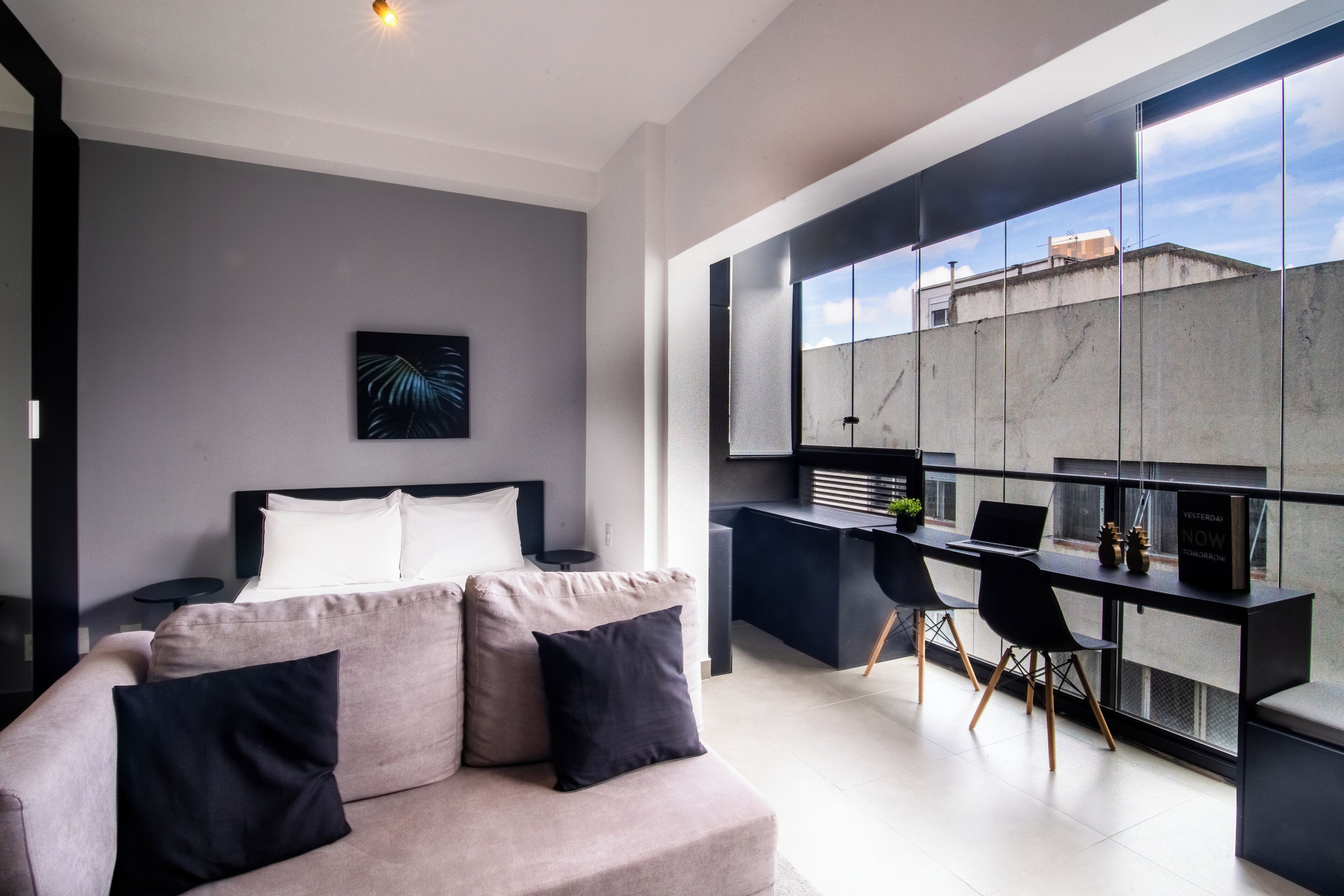 A modern bedroom with a bed, a sofa, and a desk area with a computer.