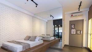 Une chambre moderne avec un mur en briques, une armoire à miroir et un lit surélevé en bois.