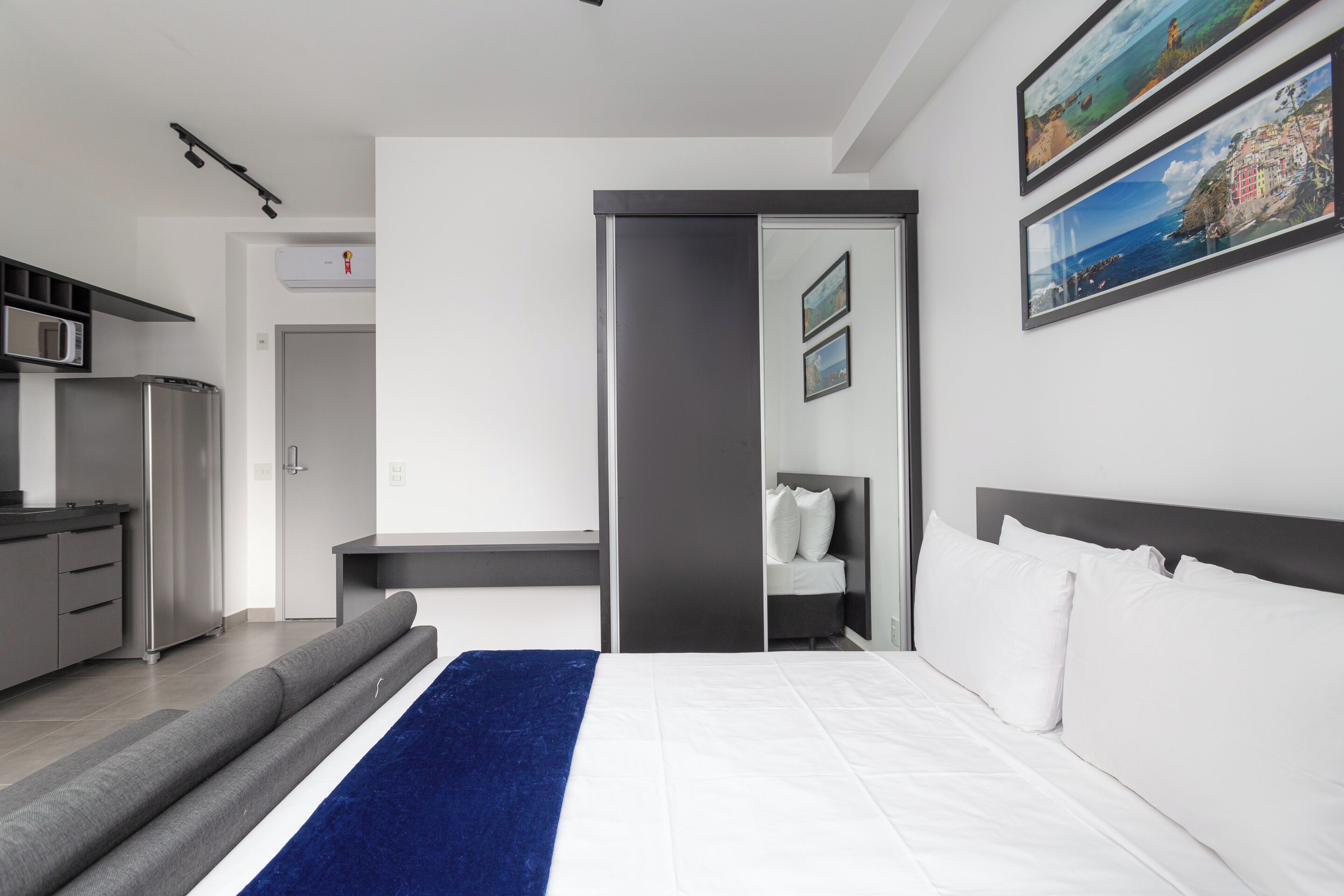 Een moderne hotelkamer met een bed, een bureau en een kitchenette.