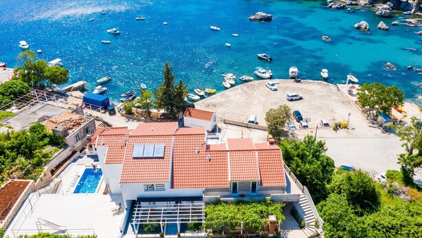 Ein Küstenanwesen mit Swimmingpool, überdachter Terrasse und Meerblick.