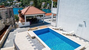 Ein Dachpool mit Fliesenplattform, überdachter Sitzgelegenheit und Blick auf die umliegenden Gebäude und das Wasser.