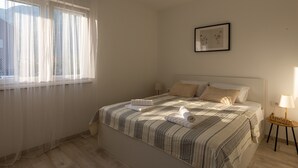 Un letto rifatto con una coperta a righe, un comodino con una lampada e un quadro appeso al muro.