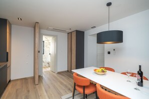 Ein stilvoller Essbereich mit einem weißen Tisch, orangefarbenen Stühlen und einer schwarzen Pendelleuchte.