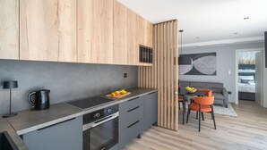 Eine moderne Küche mit einer Holzauslage, einer eingebauten Mikrowelle und einem Essbereich mit grauem Sofa und orangenen Sesseln.