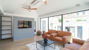 Ein modernes Wohnzimmer mit einer Couch, einem Couchtisch und einem an der Wand befestigten Fernseher.