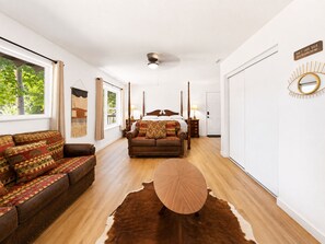 A bedroom with a four-poster bed, a sofa, a round coffee table, and a cowhide rug. - Fox & Swan Chalet (Big Bear Lake)