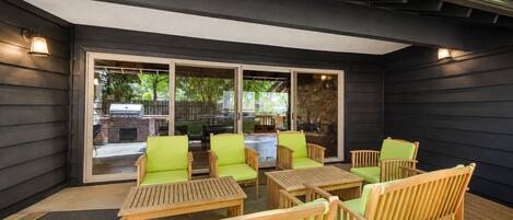 Un patio exterior con mobiliario de madera y un ventanal que da a un jardín.
