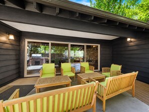 An outdoor patio with wooden furniture and a glass door leading to a backyard. - Fox & Swan Chalet (Big Bear Lake)