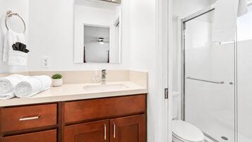 A modern bathroom with a white sink, wooden vanity, and a glass shower enclosure.
