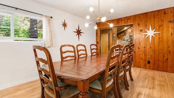 A dining area with a wooden table and chairs, a chandelier, and star decorations on the wall.