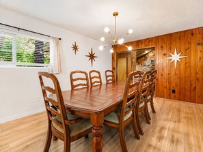A dining area with a wooden table and chairs, a chandelier, and star decorations on the wall. - Fox & Swan Chalet (Big Bear Lake)