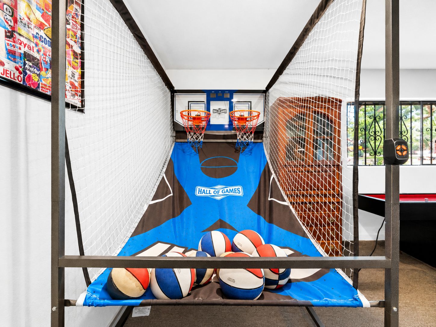 Una cancha de baloncesto con piso azul, dos aros de baloncesto y una cerca con red.