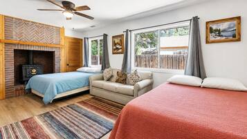 A cozy room with a fireplace, two beds, a sofa, and a window with curtains.
