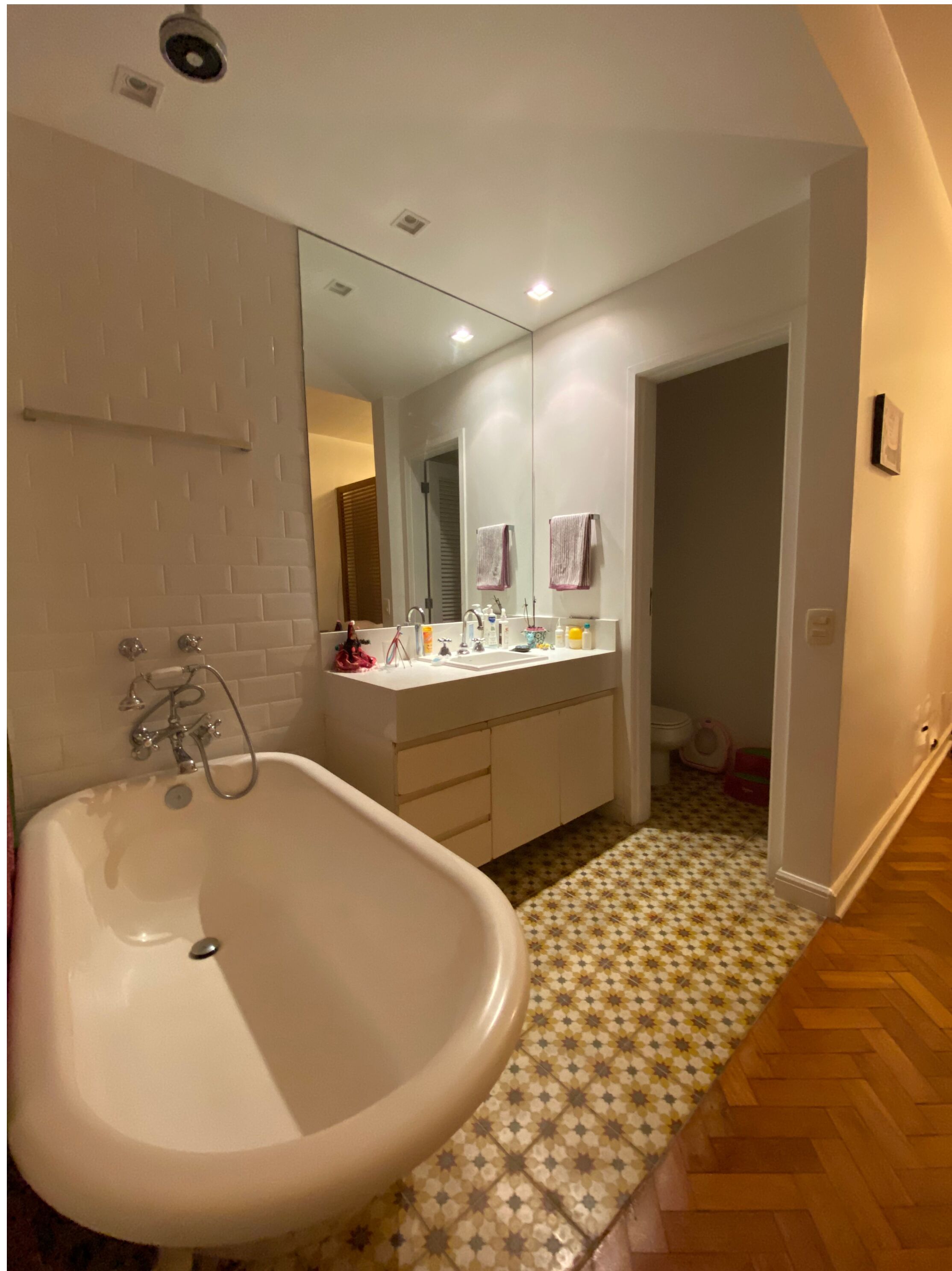 A bathroom with a large white bathtub, a double sink vanity, and a mirror above the sink.