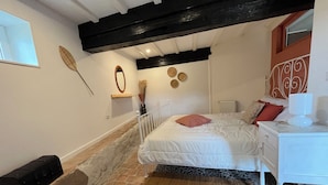 A bedroom with a bed, white dresser, and a window.