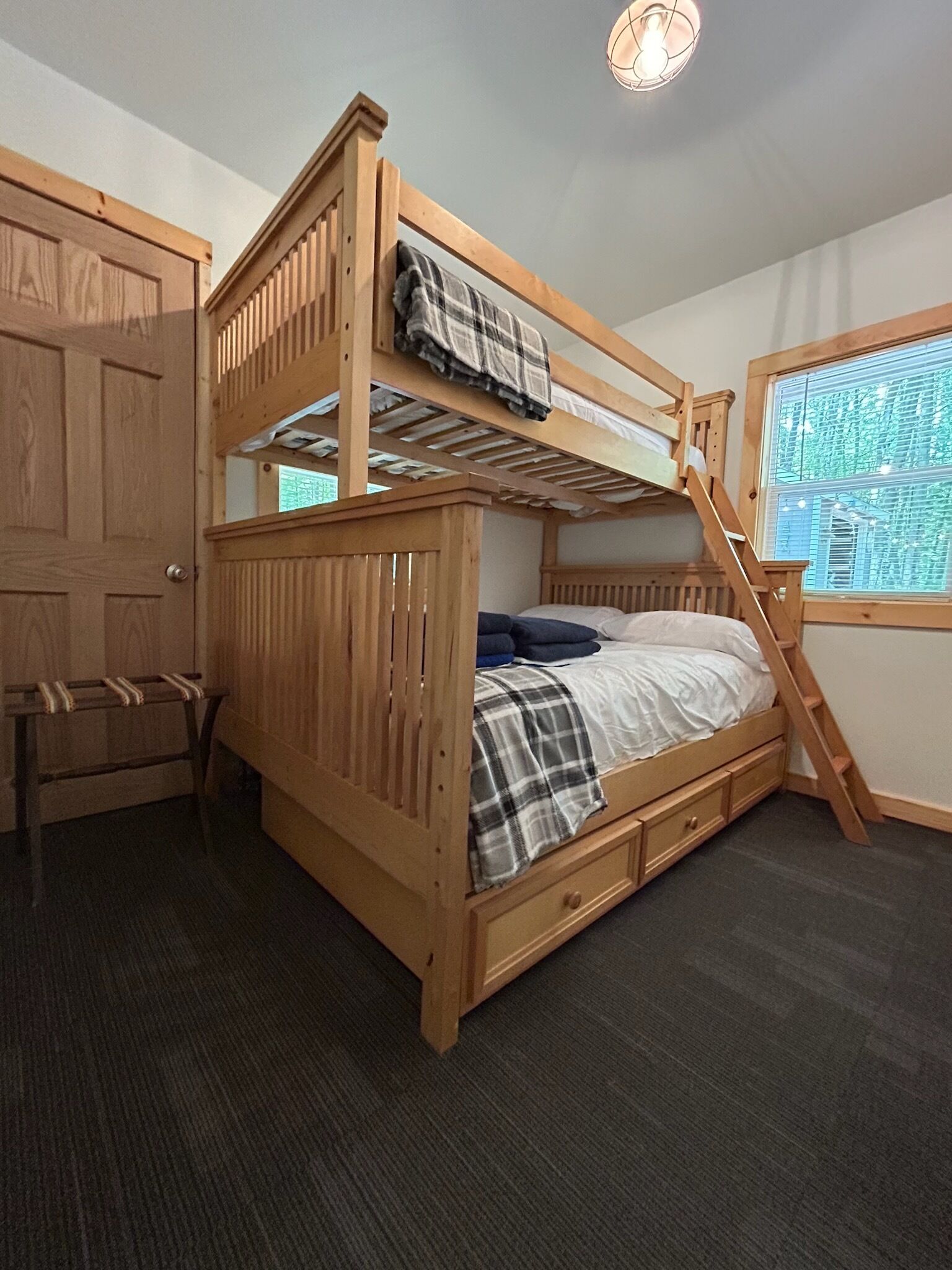 Un letto a castello con una scala in legno, una scrivania e una finestra con tende.