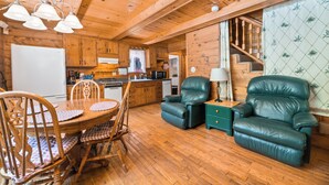 L’intérieur d’un chalet en bois comprend une table à manger, des chaises, un canapé et un escalier.