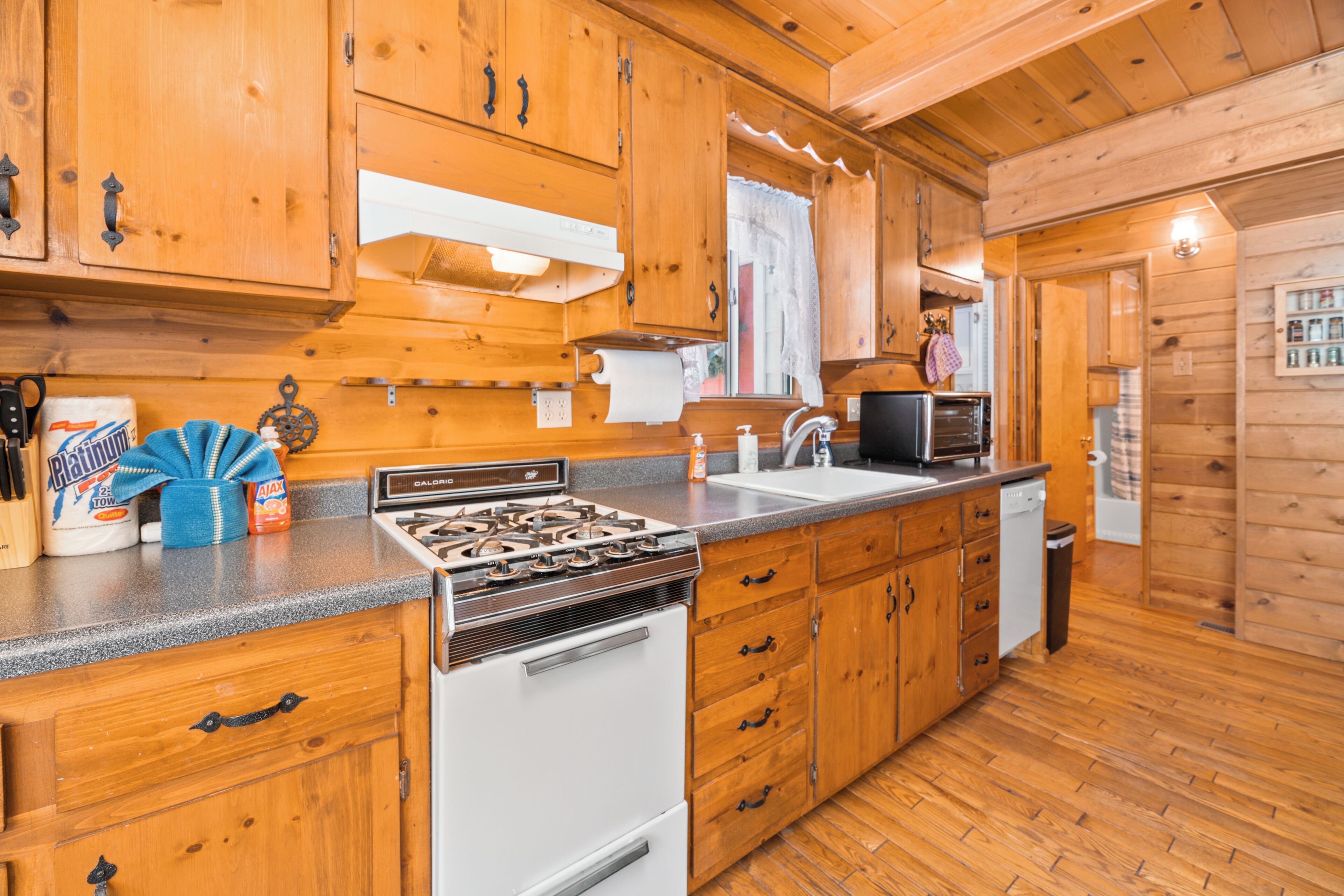 Une cuisine rustique aménagée dans une cabane en bois, avec un poêle, un évier et des placards.