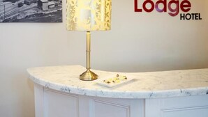 A reception desk at the Terrace Lodge Hotel with a lamp and a plate of snacks. - Terrace Lodge (Yeovil)