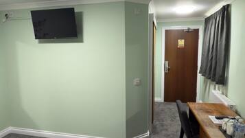 A hotel room with two beds, a desk with a chair, a television mounted on the wall, and a door leading to another room.
