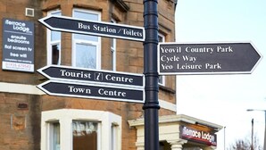 A directional signpost with multiple arrows pointing to various local attractions such as a Tourist Centre, Town Centre, Bus Station, Toilets, Yeovil Country Park, Cycle Way, and Leisure Park. - Terrace Lodge (Yeovil)