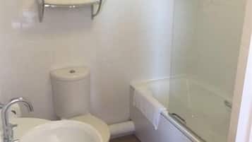 Un baño con lavamanos, inodoro y cabina de ducha acristalada.