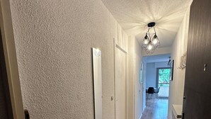 En hall med väggar som har en tydlig struktur, ett trägolv och en taklampa.