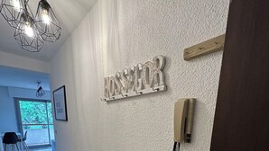 En hall med en vägg som har en intressant yta, ett metallskåp och en dörr.