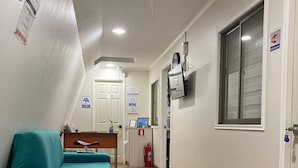 A hotel room with two beds, a desk, a TV, and a fire extinguisher.