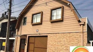 A two-story building with a brown wooden facade, a garage door, and a small window on the upper floor.