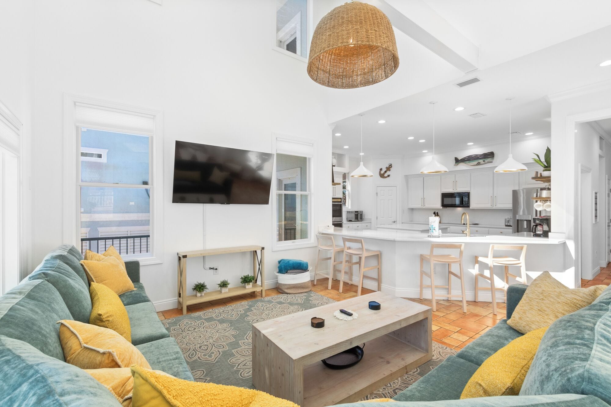 Una sala de estar moderna con un sofá grande, una mesa de centro y un televisor. Hay una zona de cocina con una mesa de comedor y sillas.