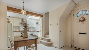 Una cocina con armarios blancos, una mesa de comedor de madera y una lámpara colgante.