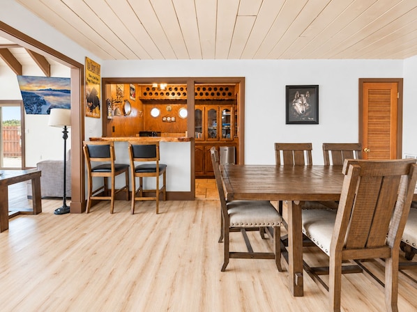 Un comedor con mesa y sillas de madera, una cocina con armarios de madera, y vistas al exterior.