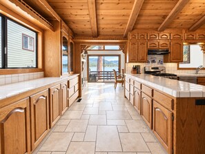 A spacious kitchen with wooden cabinetry and a large island, featuring a view of a lake and mountains.