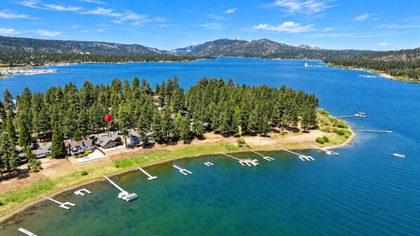 A lakeside property with a dock, boats, and a forested area.
