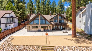 A two-story building with a deck, outdoor seating, and a sandy area.