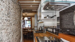 Una cocina moderna con pared de piedra, suelo de madera y vista al área de comedor.