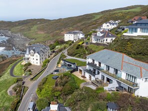 A coastal residential area with houses, a winding road, and a view of the sea.